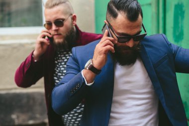 İki sakallı iş adamı telefona bakıyor.