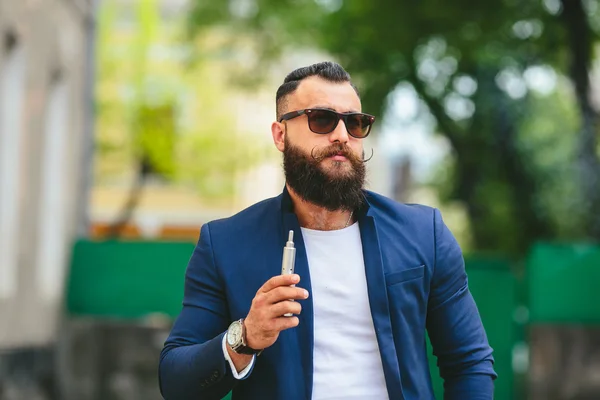 Хорошо одетый мужчина курит электронную сигарету — стоковое фото