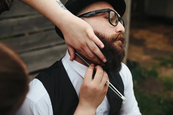 Парикмахер бреет бородатого человека на улице — стоковое фото