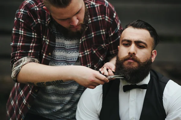 Barber shaves a bearded man Outdoors — Stock Photo, Image