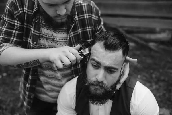 Barbiere radere un uomo barbuto all'aperto — Foto Stock