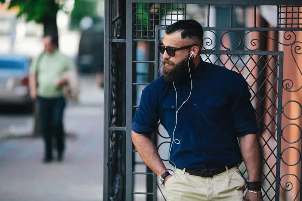 Skäggig man står och lyssnar på musik — Stockfoto