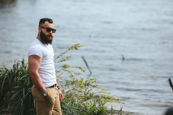 Amerikaanse bebaarde man kijkt op de rivier bank — Stockfoto