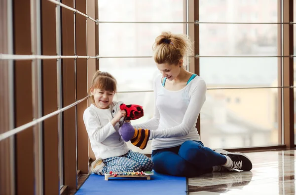 Äiti ja tytär leikkivät leluilla kuntosalilla — kuvapankkivalokuva