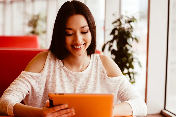 Bir tablet üzerinde çalışan ve gülümseyen güzel kız — Stok fotoğraf