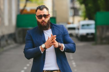 Şık sakallı adam şehirde yürüyor.