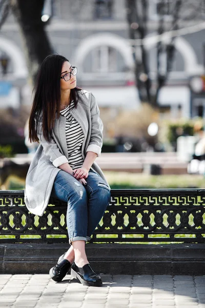 Modelo bonito em óculos sentar-se na cerca — Fotografia de Stock