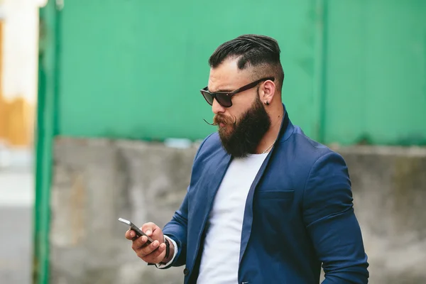 Homem de negócios barbudo olhando para o telefone — Fotografia de Stock