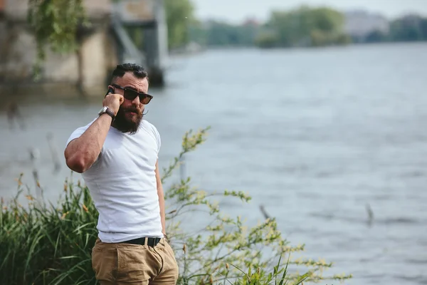 American Bearded Man utilizzando il telefono vicino al fiume — Foto Stock