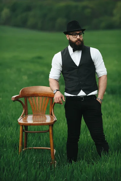 Hombre con barba, pensando en el campo cerca de la silla —  Fotos de Stock