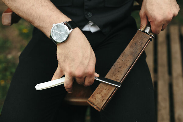 strong man sharpens old razor