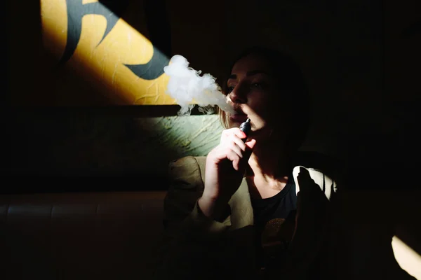 मुलगी बसते आणि इलेक्ट्रॉनिक सिगारेट धूम्रपान करते — स्टॉक फोटो, इमेज