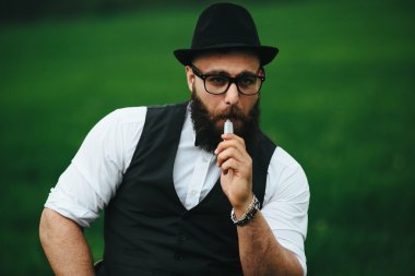 bir sakallı adam elektronik sigara içiyor