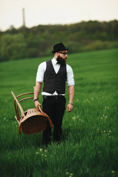 L'homme barbu porte une chaise sur le terrain — Photo