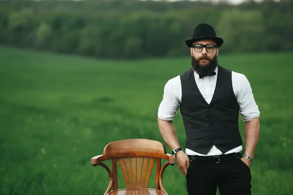Чоловік з бородою, думаючи в полі біля стільця — стокове фото