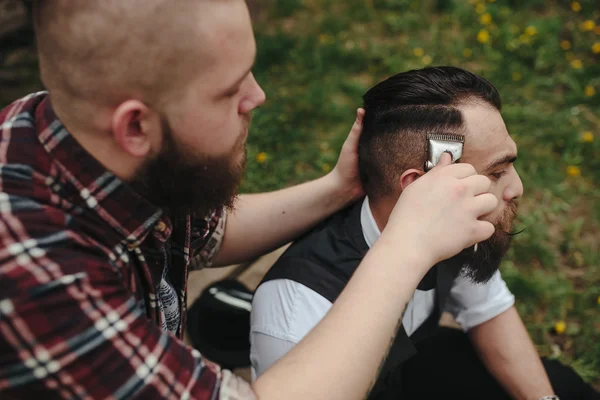 Barbero afeita a un hombre barbudo —  Fotos de Stock