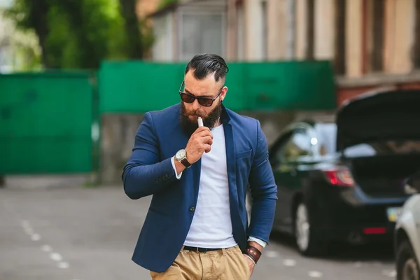 Человек с бородой курит электронную сигарету — стоковое фото