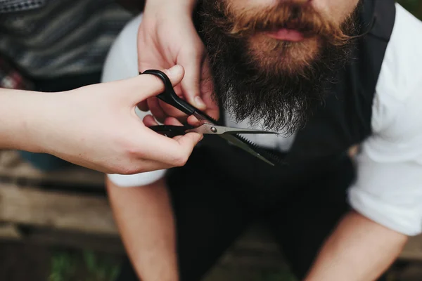 Barbero afeita a un hombre barbudo — Foto de Stock