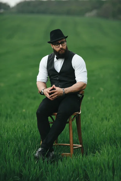 Hombre con barba, pensando en el campo cerca de la silla —  Fotos de Stock