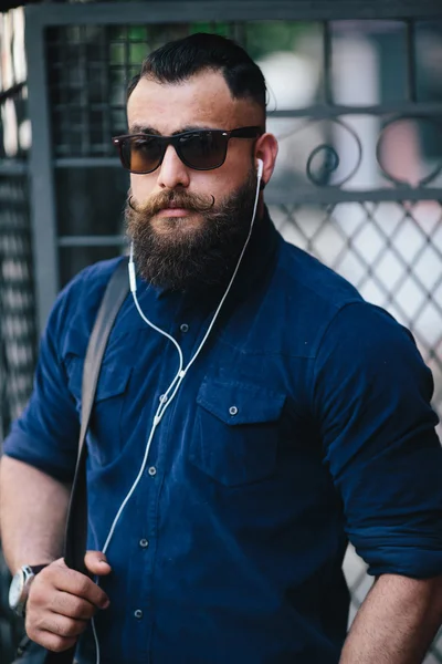 bearded man standing and listening to music