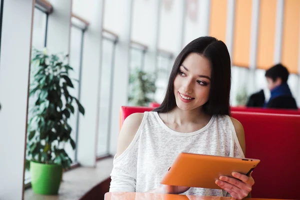 Bir tablet üzerinde çalışan ve gülümseyen güzel kız — Stok fotoğraf