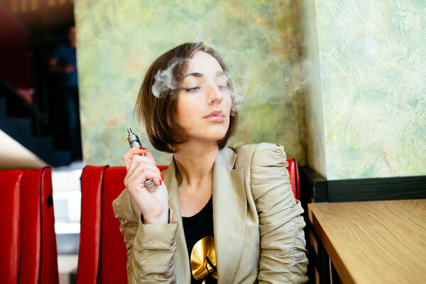 girl sits and smokes electronic cigarette