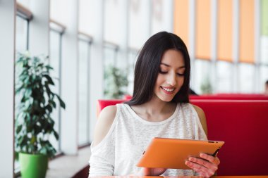 Bir tablet üzerinde çalışan ve gülümseyen güzel kız