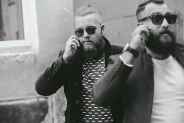 İki sakallı iş adamı telefona bakıyor.