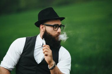 bir sakallı adam elektronik sigara içiyor