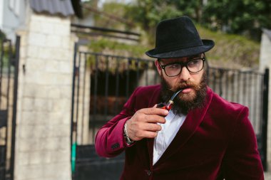 sakallı bir zengin adam beşik sigara içiyor.