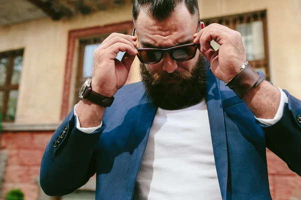 Elegante hombre barbudo fresco se quita las gafas — Foto de Stock