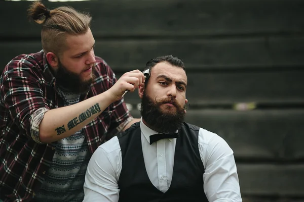 Barbero afeita a un hombre barbudo —  Fotos de Stock