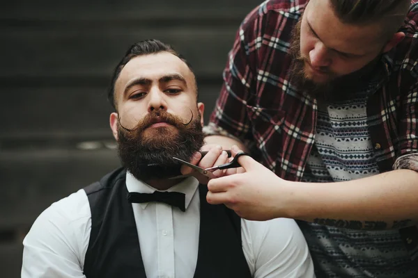 Barber shaves a bearded man — Stock Photo, Image