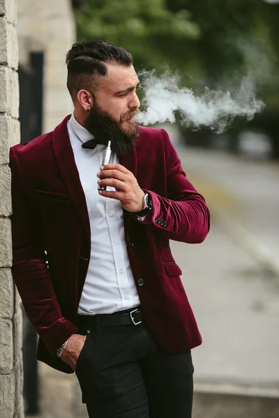 rich man with a beard smokes electronic cigarette