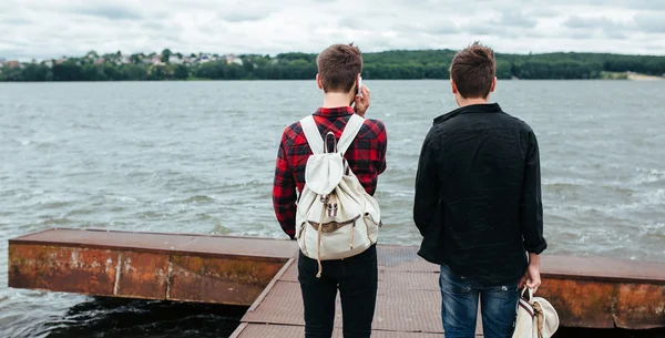 two young guys stand on the pier