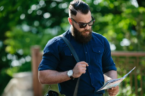 Uomo barbuto guardando una mappa — Foto Stock