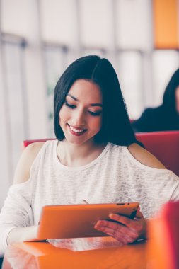 Bir tablet üzerinde çalışan ve gülümseyen güzel kız