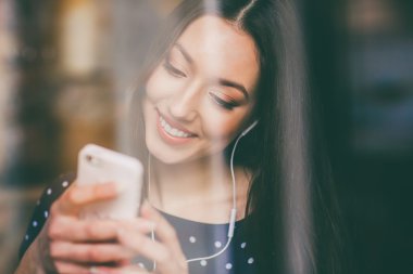 Güzel kız telefonda kulaklık ile müzik dinlemek