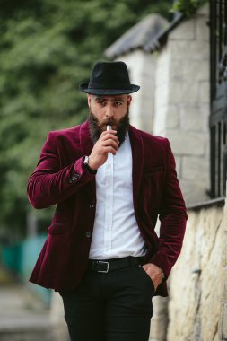 sakallı bir zengin adam elektronik sigara içiyor
