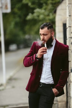 sakallı bir zengin adam elektronik sigara içiyor