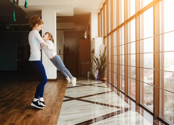 Mother twist her daughter in the gym — Stock Photo, Image