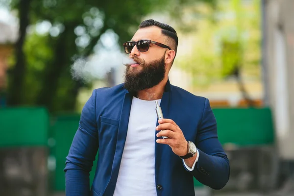 Bir sakallı adam elektronik sigara içiyor — Stok fotoğraf