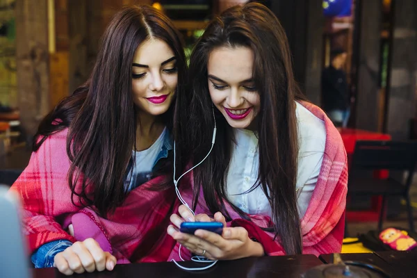 Duas meninas sentadas ouvindo música com um smartphone — Fotografia de Stock