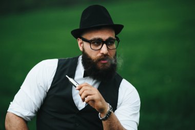 bir sakallı adam elektronik sigara içiyor