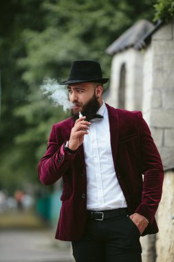 sakallı bir zengin adam elektronik sigara içiyor