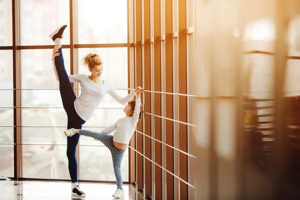 Mother learning daughter to make a high leg strech — Stock Photo, Image