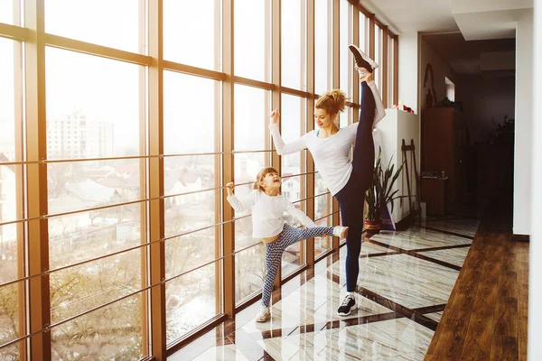 Mother learning daughter to make a high leg strech — Stock Photo, Image