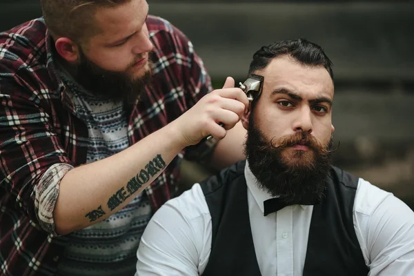 Barbero afeita a un hombre barbudo —  Fotos de Stock