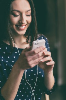 Güzel kız telefonda kulaklık ile müzik dinlemek