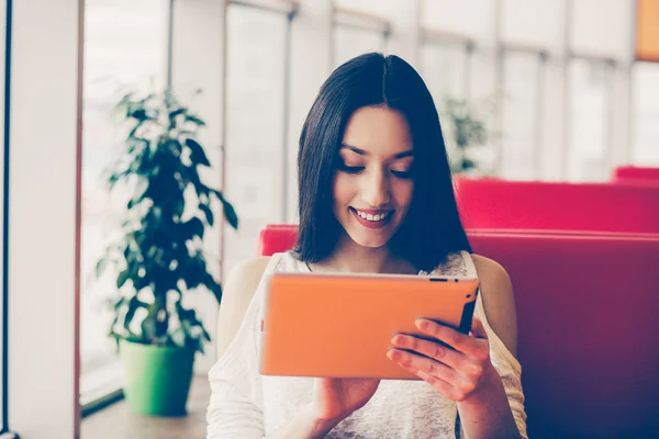 Beautiful girl working on a tablet and smiling — Stock Photo, Image